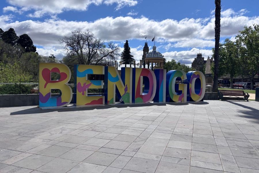 The colourful BENDIGO letters in Rosalind Park, with the historic domed building behind, in regional Victoria